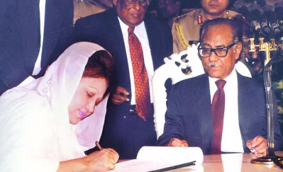 ১৯৯১ সালে প্রধানমন্ত্রী পদে শপথ শেষে শপথ-বইয়ে স্বাক্ষর করছেন খালেদা জিয়া, পাশে তৎকালীন রাষ্ট্রপতি বিচারপতি সাহাবুদ্দীন আহমদ। ছবি: সংগৃহীত