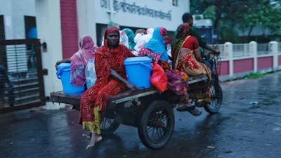 ঘূর্ণিঝড় রিমালের ক্ষয়ক্ষতি থেকে বাঁচতে ভ্যানে করে আশ্রয়কেন্দ্রে যাচ্ছেন কয়েকজন। রোববার সাতক্ষীরার শ্যামনগরে। ছবি: রয়টার্স