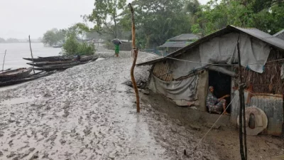 নিজের ভিটেমাটি ছেড়ে আশ্রয়কেন্দ্র যাননি অনেকে। এর মধ্যে এক নারীও রয়েছেন। তিনি বসে আছেন ঘরের দরজায়। রোববার সাতক্ষীরার শ্যামনগরে। ছবি: রয়টার্স