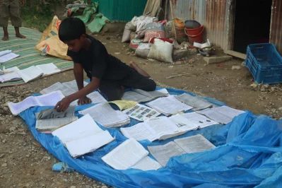 পানি থেকে তুলে বই খাতা শুকানোর চেষ্টা করছো অনিক চন্দ্র দাস। ছবি: ইনডিপেনডেন্ট