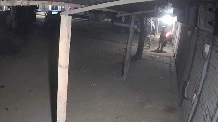 রাতের আধারে কয়েকজনকে দোকানের সামনে আগুন দিতে দেখা যায়। ছবি: সিসিটিভি ফুটেজ থেকে নেওয়া